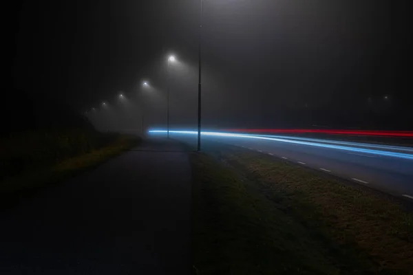 Longa Exposição Luzes Carro Uma Estrada Solitária Noite Nevoeiro Denso — Fotografia de Stock