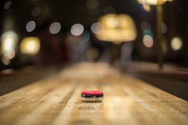 Kırmızı disk, bir shuffleboard masasının 3 puan bölgesine yaklaşıyor...