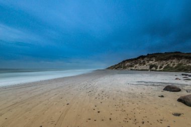 Kumsalda yuvarlanan bulutların uzun pozlama fotoğrafı..