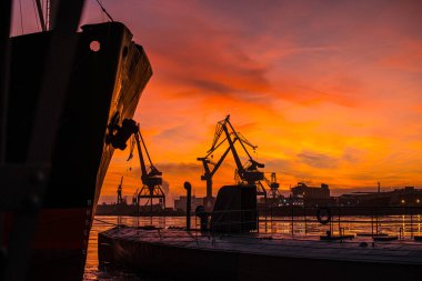 Büyük gemi ve vinçler canlı günbatımında siluetlendi