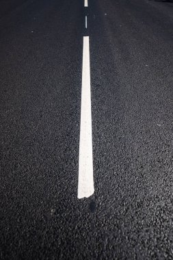 Yeni döşenmiş asfalt bir yolun beyaz merkez çizgisine yakın çekim
