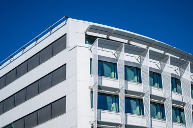 Camdan pencereleri ve beyaz dış panelleri olan modern ofis binası