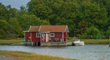 Teknesi ve yeşil ormanı olan kıpkırmızı bir kulübe.