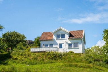 Güneşli yeşil tepede beyaz geleneksel ev