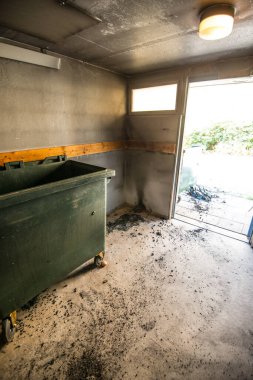 Karanlık malzeme deposunda yanmış çöp kutusu.