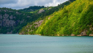 Sakin suların sakin manzarası, ormanlık tepeler ve kayalık kayalıklar..