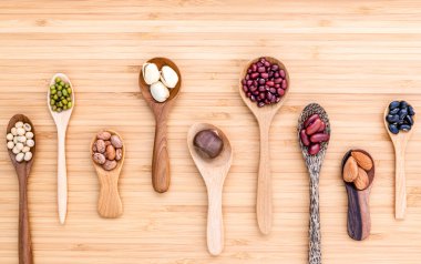 Assortment of beans and lentils in wooden spoon set up on wooden