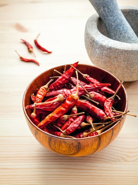 Torkade chili på vit trä bakgrund med mortel och stöt — Stockfoto