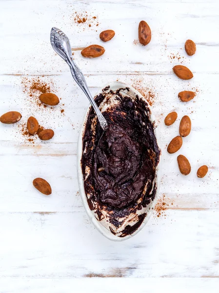 Chocolate derretido com colher de metal em tigela de cerâmica e coco assado — Fotografia de Stock