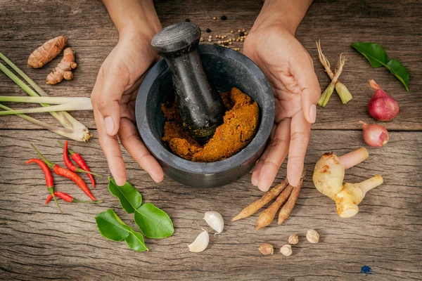 Las mujeres sostienen mortero con mortero y pasta de curry rojo picante ingr —  Fotos de Stock