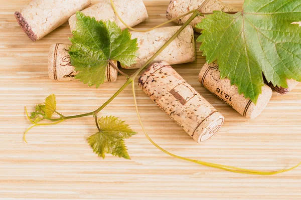 Composition of wine corks with grape vine and leaves on wooden t — Stock Photo, Image