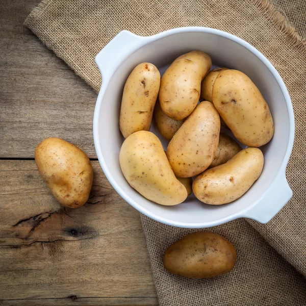 Composition of fresh organic potatoes in white ceramic bowl on h — Stock Photo, Image