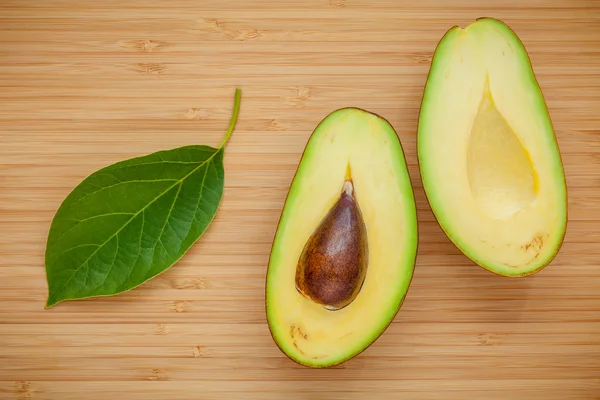 Концепция здорового питания. Крупный план спелых авокадо с листьями авокадо о — стоковое фото