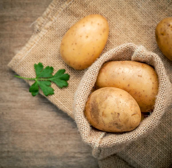 Closeup fresh organic potatoes in hemp sake bag with parsley on — Stock Photo, Image