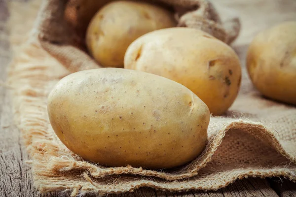 Closeup fresh organic potatoes on hemp sack background. Row orga — Stock Photo, Image