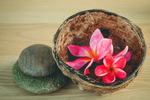 Aromatische olie in de kokosnoot schelp met Spa stenen en Frangipani — Stockfoto