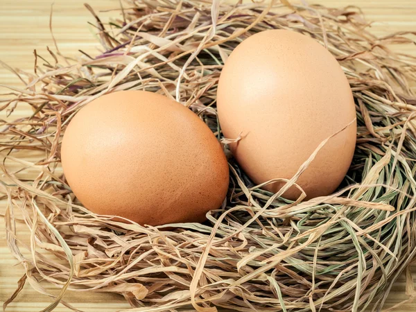 Closeup brown chicken eggs in a straw nest . Fresh organic eggs — Stock Photo, Image