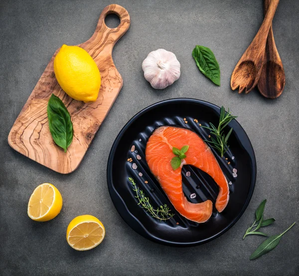 Filé de salmão cru no prato preto com ingredientes azeite — Fotografia de Stock
