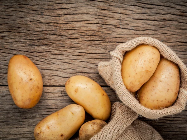 Fresh organic potatoes in hemp sake bag on rustic wooden backgro — Stock Photo, Image