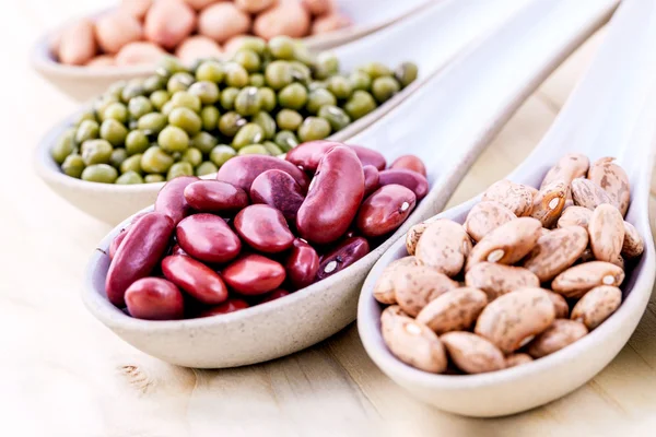 Assortment of beans and lentils in wooden spoon isolate on white