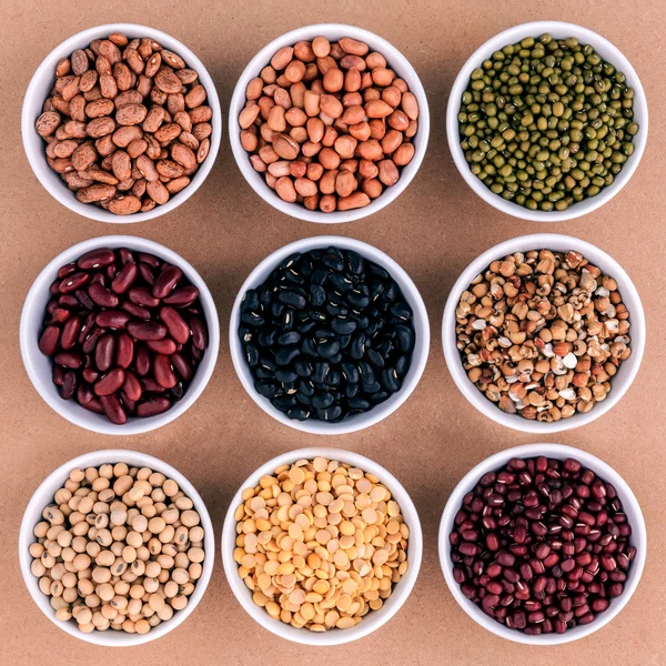 Mixed beans and lentils in the white bowl  on brown background.