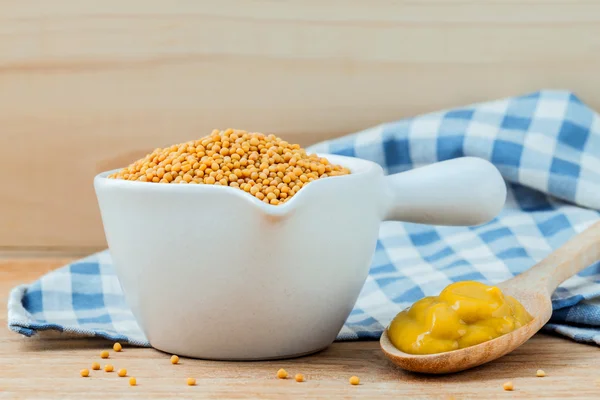 Composition of mustard and mustard seeds on wooden background. Royalty Free Stock Images