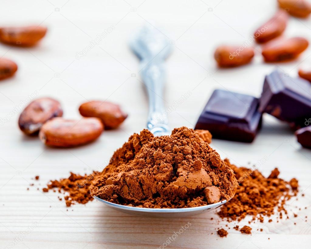 Brown chocolate powder in spoon , Roasted cocoa beans and dark c