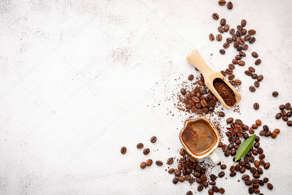 Background of various coffee , dark roasted coffee beans , ground and capsules with scoops setup on white concrete background with copy space.