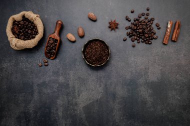 Kahve tozu ve lezzetli malzemelerle kavrulmuş kahve çekirdekleri koyu taşlı arka planda lezzetli kahve yapmak için..