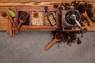 Ahşap kutuda bir sürü kavrulmuş kahve çekirdeği ve köhne ahşap arka planda el yapımı kahve öğütücüsü..