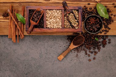 Ahşap kutuda bir sürü kavrulmuş kahve çekirdeği ve köhne ahşap arka planda el yapımı kahve öğütücüsü..