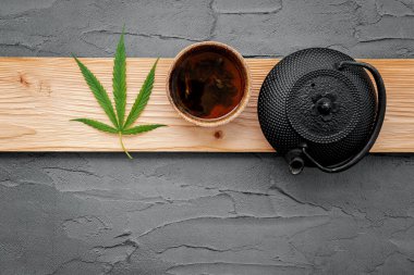 Esrar, bitki çayı ve çimento üzerine taze marihuana yaprakları serpiştirilmiş klasik çaydanlık..