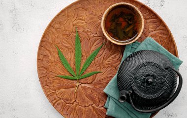 Esrar, bitki çayı ve çimento üzerine taze marihuana yaprakları serpiştirilmiş klasik çaydanlık..