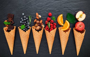 Böğürtlenli, limonlu, şam fıstıklı, bademli, portakallı, çikolatalı, vanilyalı ve koyu taştan arkaplanlı kahveli dondurma için çeşitli malzemeler. Yaz ve Tatlı menü kavramı.