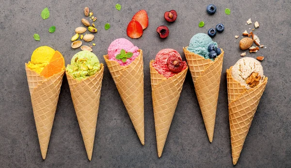 Various of ice cream flavor in cones blueberry ,strawberry ,pistachio ,almond ,orange and cherry setup on dark stone background . Summer and Sweet menu concept.