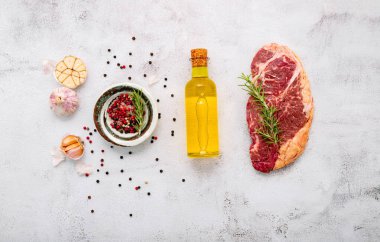 Beyaz beton arka planda çiğ Striplion bifteği. Biberiyeli taze biftek ve baharatla bembeyaz, köhne beton arka plan manzaralı..