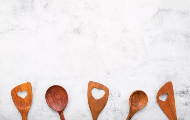 Ahşap mutfak aletlerinden yapılmış çeşitli kalp şekilleri. Tahta kaşıklar ve beyaz beton zemin üzerinde tahta spatula düz yatar ve boşluğu kopyalar.