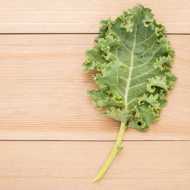 Taze organik kıvırcık lahana yaprakları ahşap bir masanın üzerinde duruyor..