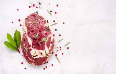 Beyaz beton arka planda çiğ kaburga gözü bifteği. Biberiyeli taze biftek ve baharatla bembeyaz, köhne beton arka plan manzaralı..