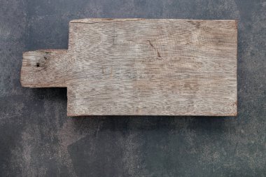 Boş eski tahta kesme tahtası kopyalama alanı olan koyu beton arkaplan üzerine kurulmuş.