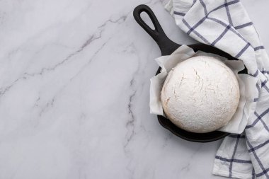 Taze çiğ hamur mayası mermer masa üzerinde dökme demir tavada dinleniyor..