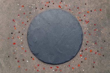 Koyu beton zemin üzerine baharatlı boş bir pizza tabağı döşeme ve kopyalama alanı.