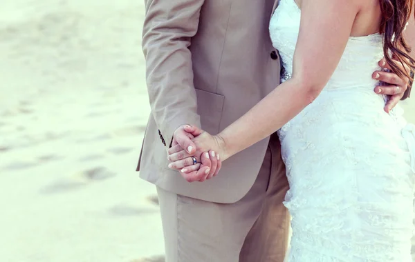 Hände des Brautpaares mit Eheringen am tropischen Strand. — Stockfoto