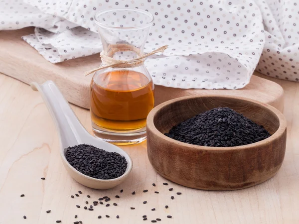 Zřídit černý sezamový olej a Sezamová semínka na dřevěný stůl — Stock fotografie