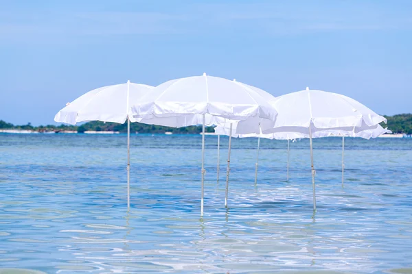 Guarda-chuva branco na praia tropical de verão com barco à vela . — Fotografia de Stock