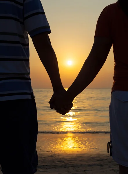 Silhouettes couples holding hands on sunset.