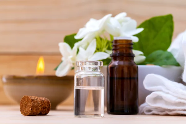 Aroma oil bottles arranged with jasmine flowers on wooden backgr