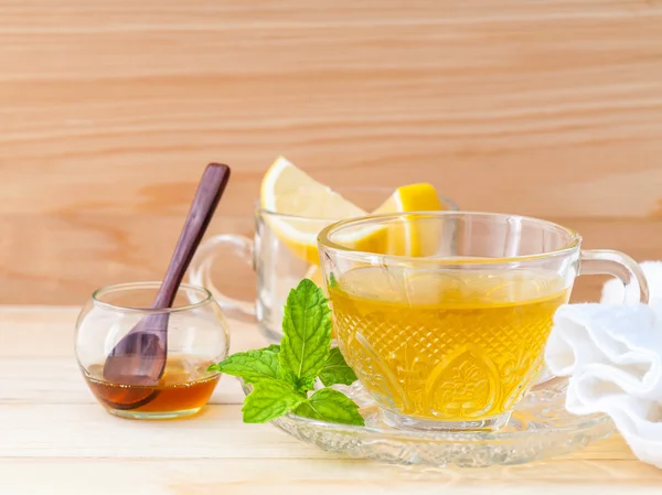Чашка травяного чая со свежей зеленой мятой, медом и лимоном на дереве — стоковое фото
