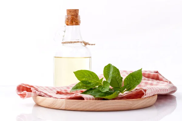 Branch of fresh  basil in wooden plate with olive oil on cutting — Stock fotografie