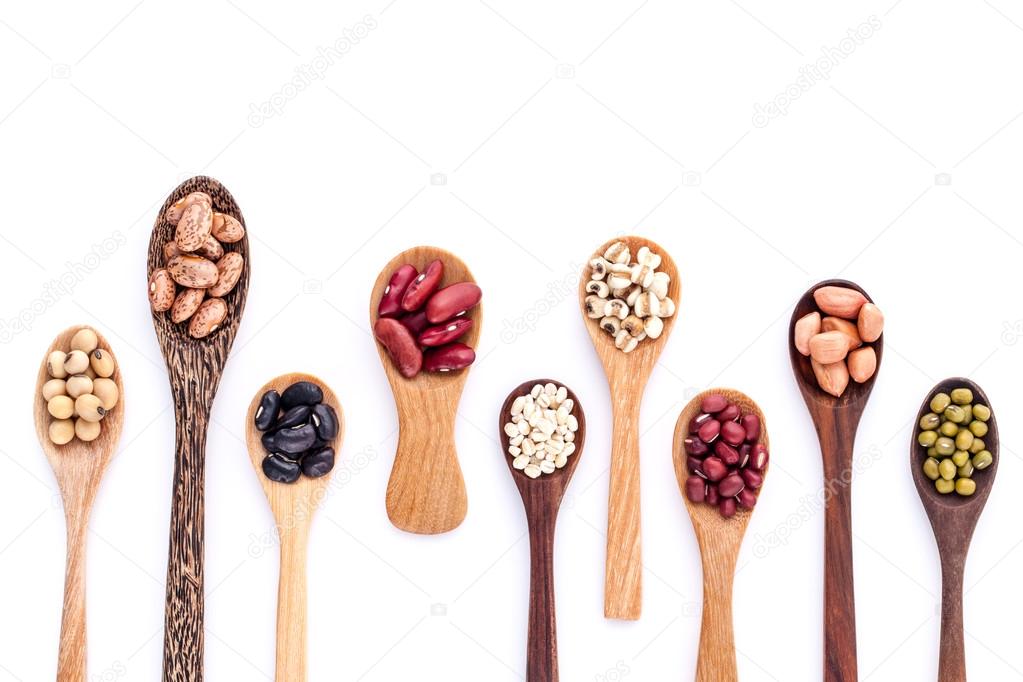 Assortment of beans and lentils in wooden spoon isolate on white